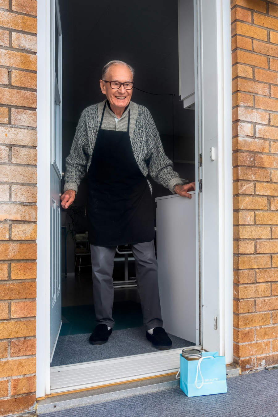 Senior man comfortably at the front door of his own home