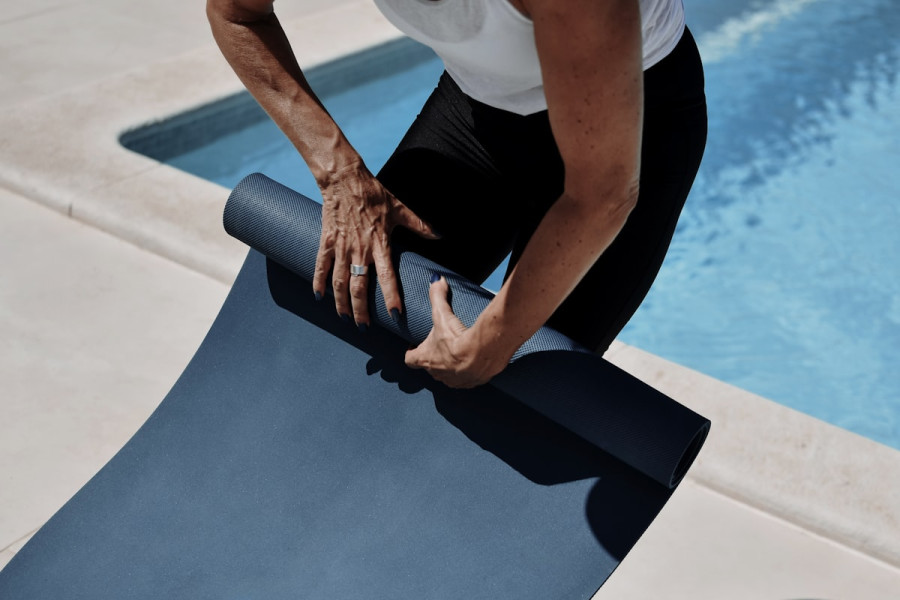 Hands rolling up a yoga mat after a session